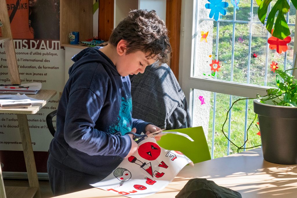Un jeune garçon fait une activité de découpage à la Maison des Familles.