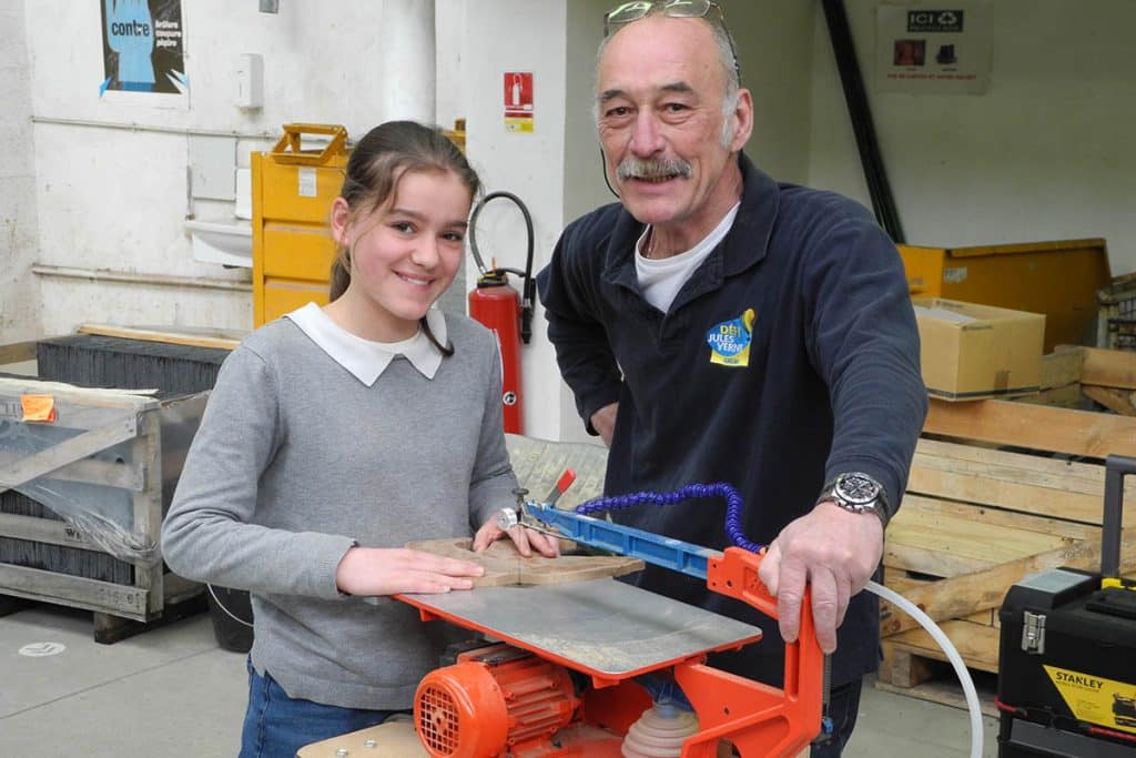 Une jeune fille est initiée aux métiers de l’artisanat et du patrimoine par un retraité bénévole.