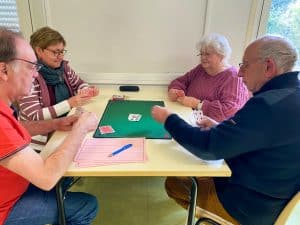 Deux hommes et deux femmes jouent à la belote.